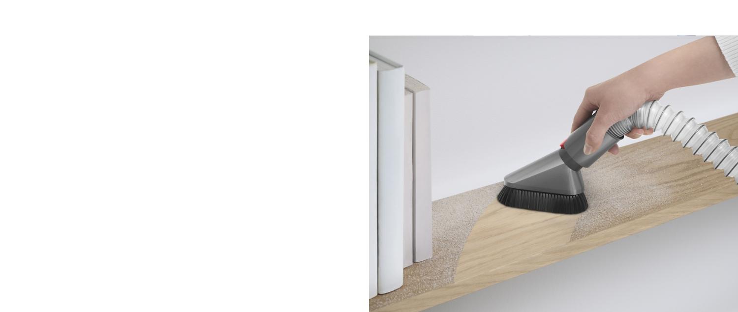 Person using the Dyson Extension hose with the Mini soft dusting brush attachment to vacuum dust on a shelf